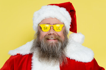 Wall Mural - smiling and chubby man in christmas costume and glasses with sale lettering isolated on yellow.