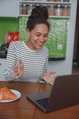 Wall Mural - portrait of joyful beautiful young woman speaking on video call using laptop indoor