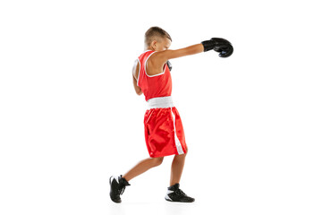 Portrait of active boy, beginner boxer in sports gloves and red uniform isolated on white background. Concept of sport, movement, studying, achievements, lifestyle.