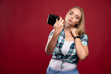 Wall Mural - Young blonde photograph holding a professional camera and takes her selfie in lovely and confident positions