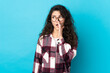 Teenager Russian girl isolated on blue background whispering something with surprise gesture while looking to the side