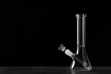 Glass Bong On Grey Table Against Black Background, Space For Text. Smoking Device