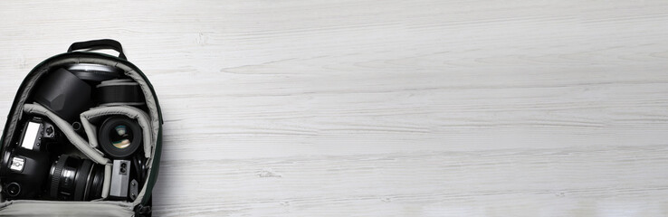 Wall Mural - professional photography equipment in backpack on white wooden table, top view with space for text. 