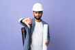 © luismolinero - Young architect Moroccan man with helmet and holding blueprints over isolated background showing thumb down with negative expression