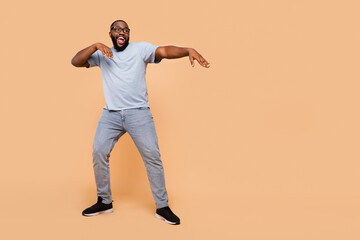 Wall Mural - Full length body size view of attractive cheerful guy moving having fun copy space isolated over beige pastel color background