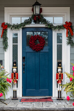 Navy Blue Front Door Of A House Home Decorated For Christmas With A Wreath And Garland And Two Nutcrackers