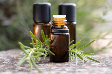 Wall Mural - Close-up of three brown bottles with natural rosemary essential oil