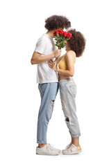 Wall Mural - Full length profile shot of casual young couple hugging and holding a bunch of red roses