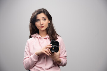 Wall Mural - Female photographer with camera standing on gray background