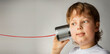© Chepko Danil - Boy listen Tin Can Phone play with retro toy. Isolated on grey Background