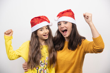 Wall Mural - Woman hugging young girl with Santa Claus red hat