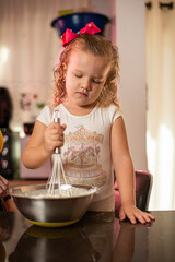 Imagem de mãe e filha brincando enquanto cozinham um bolo. Mulher loira brincando com sua filha na cozinha. Receita de doce feita em família.