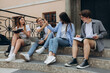 © Igor - Confident students. Group of happy young people working together and looking at laptop while sitting on steps
