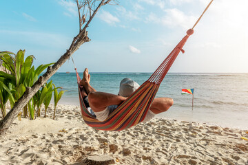 Tourist relaxing in a hammock on a tropical beach overlooking the Indian Ocean. La Digue island, Seychelles