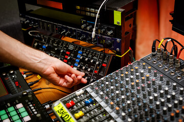 Wall Mural - Hand of a sound engineer on sound console mixer. Equalizer control