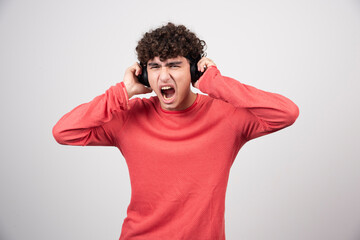 Wall Mural - Curly young man with headphones listening to song with loud volume