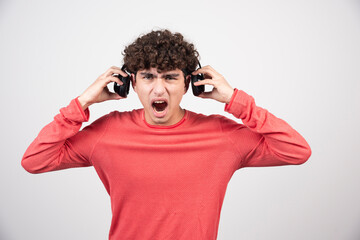 Wall Mural - Young man listening to music with headphones angrily