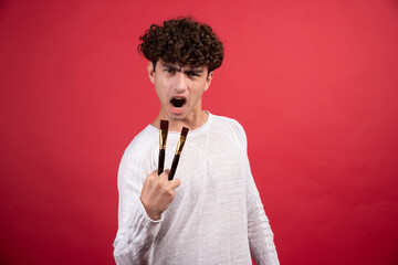 Wall Mural - Male painter with brushes screaming on red background