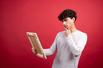 Wall Mural - Young man looking at empty canvas with thoughtful gaze