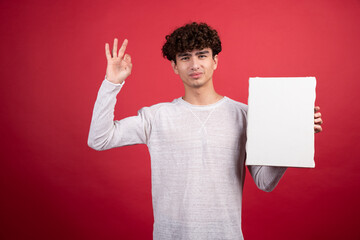 Wall Mural - Young man with empty canvas giving ok sign