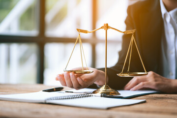 Wall Mural - Close up of lawyer's hands and scale of justice on table in the office.