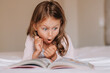 Emotional child girl read interesting book in bed. Small kid enjoy reading. Fantasy and fantastic. Developing child fantasy and imagination. Imaginary world. Fairy tale. Bedtime reading