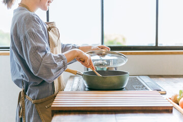 キッチンで調理するエプロン姿の女性
