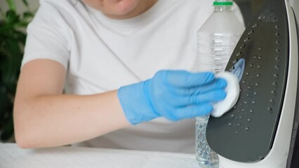 Wall Mural - A woman cleans the sole of an iron with vinegar. Folk methods of cleaning iron contaminants