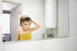 © natalialeb - Cute toddler baby combs in front of bathroom mirror