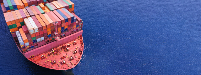 Wall Mural - Aerial drone ultra wide photo of bow from huge fully loaded container tanker ship carrying truck size colourful containers in deep blue open ocean sea