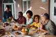© Drazen - Happy multiethnic family enjoys while having meal at dining table on patio.