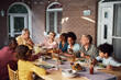 © Drazen - Happy multiethnic extended family eating at dining table on patio.