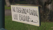 No Fishing Or Diving Off Bridge Swinging Sign. Cartoon Style Font.