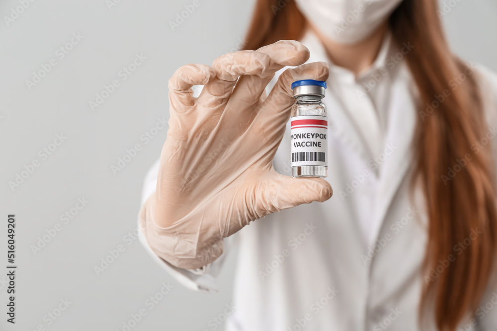 Female doctor with monkeypox vaccine on light background, closeup