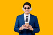 stylish asian businessman wearing formal suit and headphone sunglasses hand choosing song playlist from smartphone application device relax casual leisure lifestyle after work smiling cheerful moment