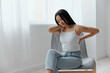 © SHOTPRIME STUDIO - Back pain. Suffering from osteochondrosis after long study work pretty young Asian woman touching painful lower back at home interior living room. Injuries Poor health Illness concept. Cool offer