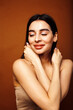 © iordani - Cute happy young indian woman on brown background in studio close up smiling, fashion beauty warm tanned
