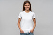 Young woman in casual white t-shirt standing with hands in pockets