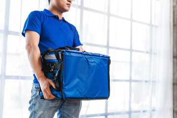 Young Asian man holding food bag and standing inside of the studio, delivery box concept.