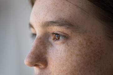 Side profile view face of freckled serious pensive woman staring aside. Close up cropped image of thoughtful young 18s female looking into distance. Concept of vision care, eyesight check up in clinic