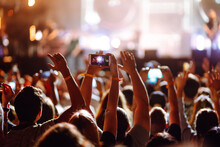 Using A Smartphone In A Public Event, Live Music Festival. Holding A Mobile Phone In Hands And Shooting Photo Or Video Content. Youth, Party, Vacation Concept.