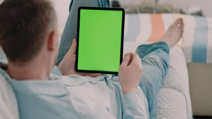 unrecognizable man lying on a couch wearing casual shirt using digital tablet with green screen leisure time at home