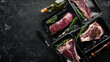 © Yaruniv-Studio - Set of beef steak in vacuum packing. Market. Top view. Flat lay top view on black stone cutting table.