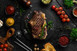 cowboy steak with spices on a stone background, first-class rib on the bone, top view. On a black stone background.