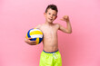 Little caucasian boy playing volleyball isolated on pink background proud and self-satisfied