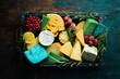 Big set of cheeses with snacks in a wooden box. On a black stone background. Free copy space.