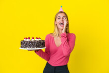 Blonde Uruguayan Girl Holding Birthday Cake Isolated On Yellow Background Shouting With Mouth Wide Open