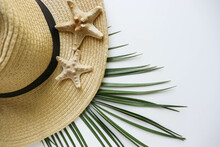 Summer Holiday Concept. Romantic Composition Of Straw Hat, Palm Leaf And Sea Shells