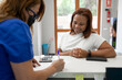 © StockRojoVerdeyAzul - A dentist woman writes some indications for her black woman client at the counter of the dental clinic's hall