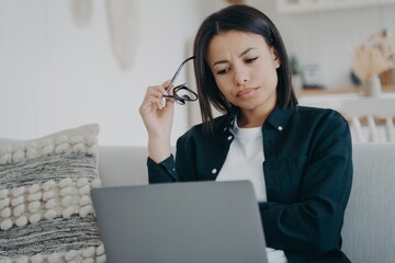 Focused businesswoman frowning works on business project at laptop at home. Stress at work, overtime